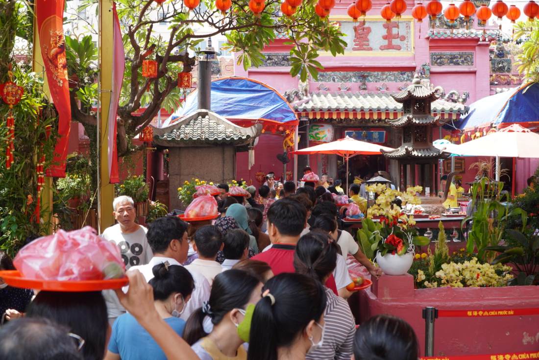 Bên trong chùa, hàng trăm người đang xếp thành hàng dài, trên tay mang theo lễ chờ tới lượt để vào chính điện.
