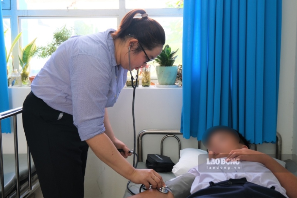 Chị Lê Thị Tuyền Duy kiểm tra sức khỏe cho em Ngô Thiên Quang - học sinh từng té ở trường và được cô sơ cấp cứu. Ảnh: Phong Linh.