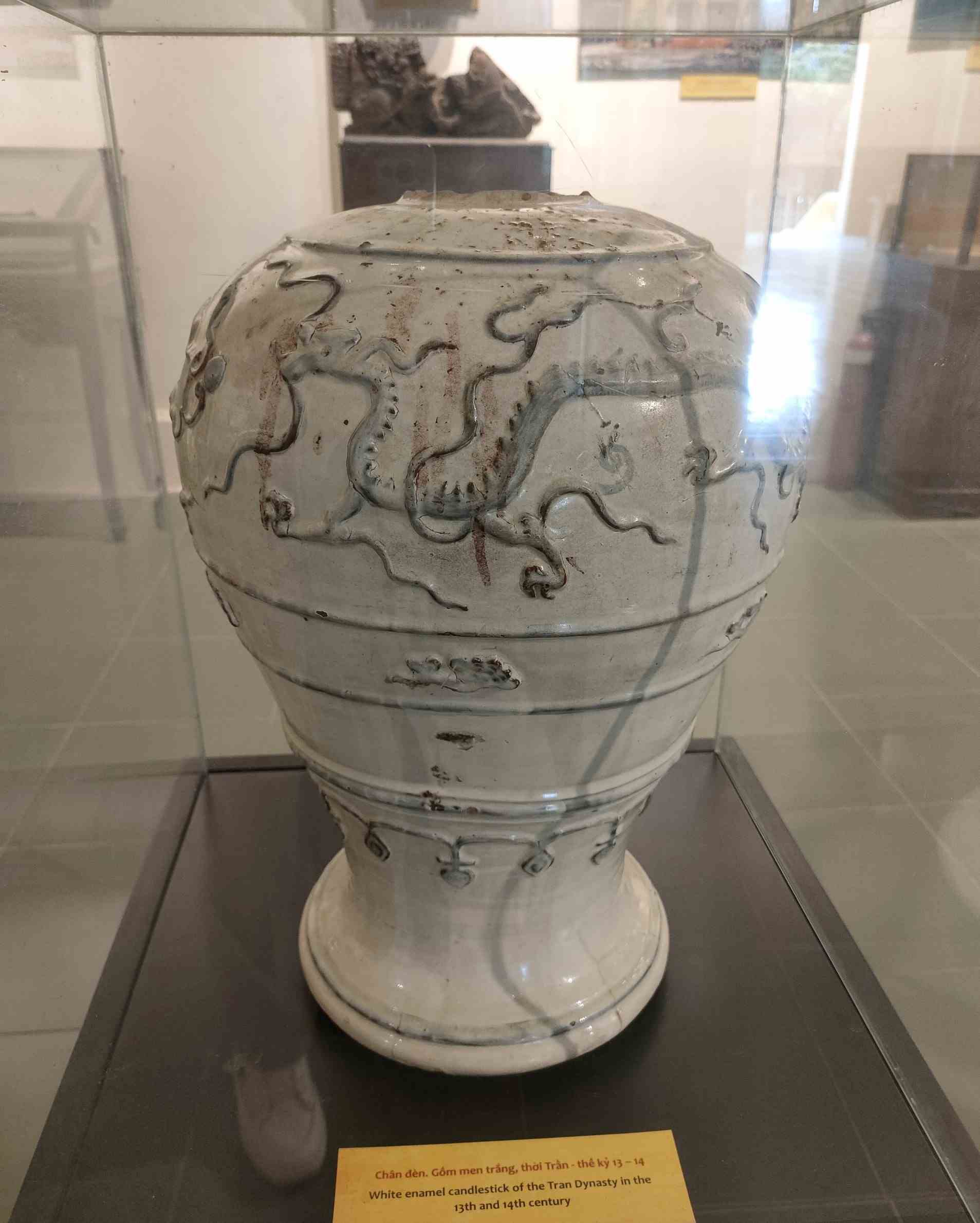 Chân đèn làm từ gốm men trắng là hiện vật thời Trần - thế kỷ 13-14. Chân đèn được trang trí hình rồng cưỡi mây uốn lượn.