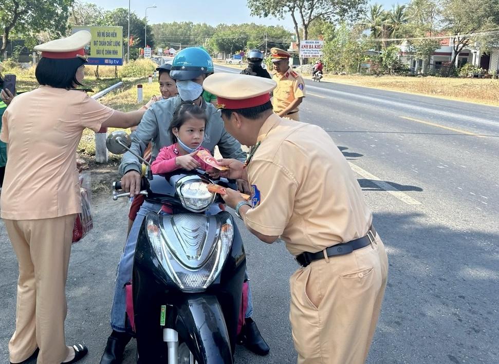 Trung tá Vũ Mạnh Hà, Trạm trưởng Trạm CSGT Hàm Tân, Bình Thuận tặng bao lì xì tiền cho trẻ nhỏ trên xe máy về quê cùng bố mẹ. Ảnh: Duy Tuấn 