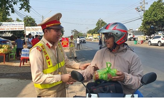 Lực lượng chức năng tỉnh Đắk Lắk hỗ trợ cấp phát nước uống, khăn lạnh, bánh mì và tặng mũ bảo hiểm cho người dân về quê ăn Tết. Ảnh: Công an cung cấp