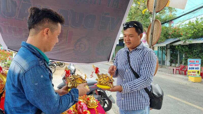 Anh Trần Thanh Tâm thường mua sản phẩm tạo hình linh vật từ trái dừa của anh Trương Quốc Kỳ. Ảnh: Hoàng Lộc