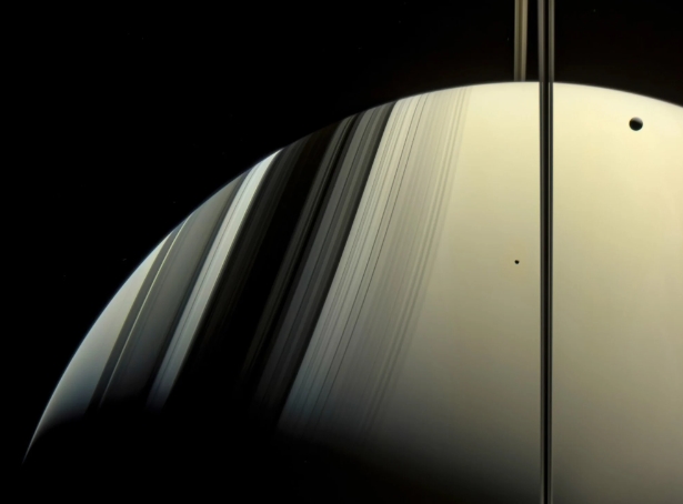Minas xuất hiện dưới dạng một chấm nhỏ phía trên sao Thổ, ở bên trái của bóng vòng thẳng đứng. Tethys, mặt trăng lớn hơn của sao Thổ, ở góc trên bên phải. Ảnh: NASA