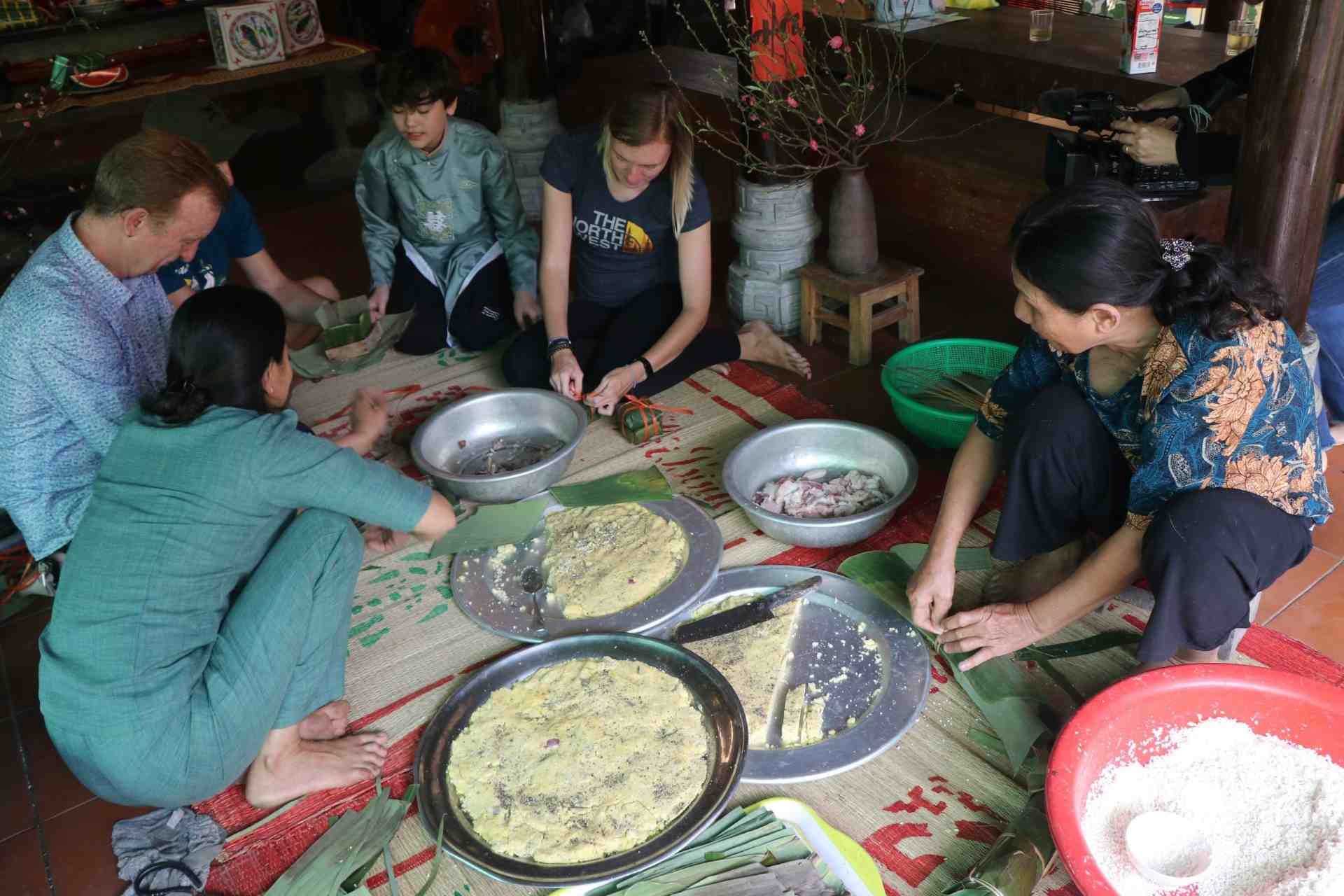 Du khách trải nghiệm gói bánh chưng dịp Tết cổ truyền của dân tộc Việt Nam. Ảnh Quảng An.