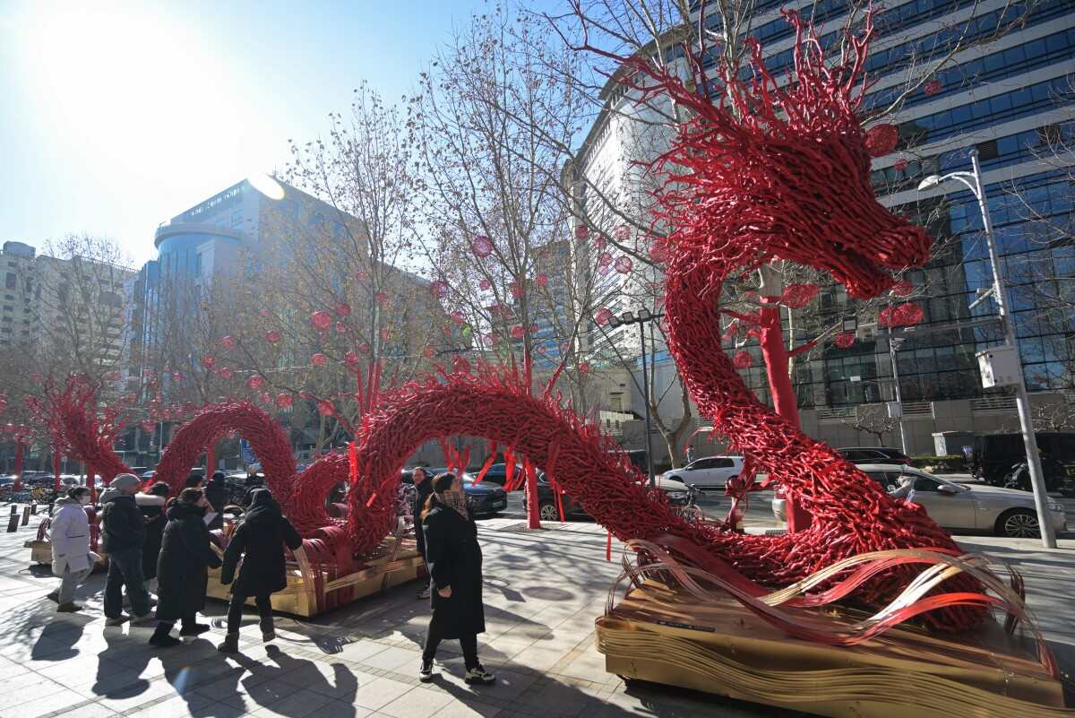Du khách ngắm tượng rồng làm từ cành cây khô trên đường phố Bắc Kinh, Trung Quốc trước thềm Tết Nguyên đán Giáp Thìn 2024. Ảnh: AFP