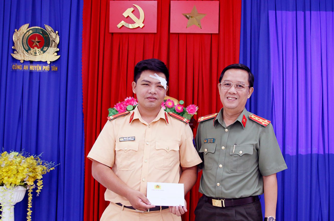 Đại tá Lê Phú Thạnh (phải) tặng quà hỗ trợ trung úy Nguyễn Quốc Thái bị thương do đối tượng vi phạm tông xe. Ảnh: Vũ Tiến