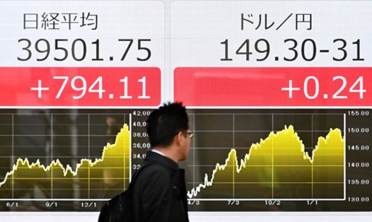 Bảng điện tử hiển thị giá cổ phiếu của Sở giao dịch chứng khoán Tokyo (trái) và tỉ giá đồng Yên so với đồng USD (phải) trên đường phố Tokyo ngày 18.3.2024. Ảnh: AFP