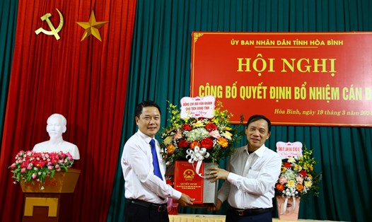 Chủ tịch UBND tỉnh Hòa Bình trao quyết định và tặng hoa chúc mừng ông Bùi Ngọc Đại (bên trái). Ảnh: Hương Lan