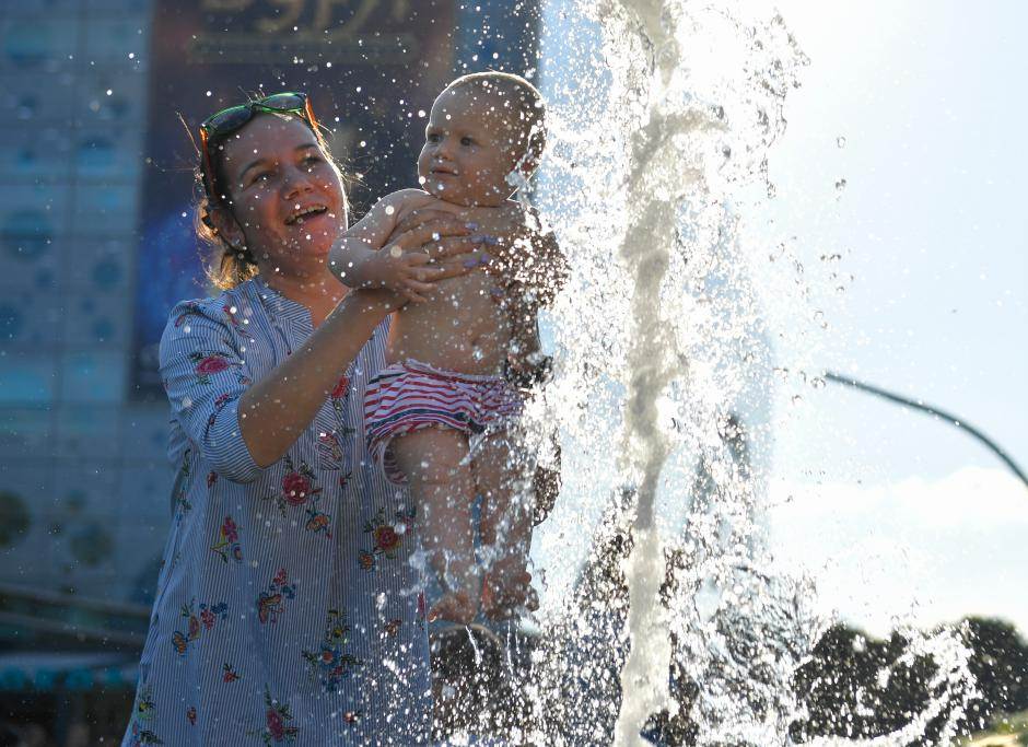 Mẹ cho bé tắm giữa nắng nóng ở Mátxcơva, Nga, ngày 5.8.2023. Ảnh: Xinhua