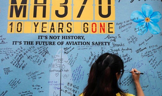 Một phụ nữ đang ghi lưu bút dịp kỷ niệm 10 năm MH370 mất tích. Ảnh chụp màn hình Yahoo News