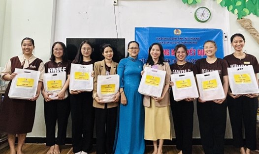 Bà Hồ Thị Đoan Trang - Chủ tịch LĐLĐ TP Huế - tặng áo dài cho các nữ đoàn viên tại Công ty TNHH Đầu tư và Phát triển Giáo dục Kindle. Ảnh: Xuân Thịnh