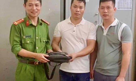Anh Thọ (ở giữa) bàn giao túi xách chứa 8 triệu đồng mà mình nhặt được cho công an để trả lại người đánh rơi. Ảnh: Quang Lộc.