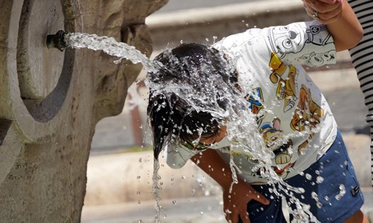 Du khách làm mát bằng nước từ Đài phun nước Barcaccia ở quảng trường Piazza di Spagna ở Rome, Italy trong đợt nắng nóng mùa hè 2023. Ảnh: Xinhua