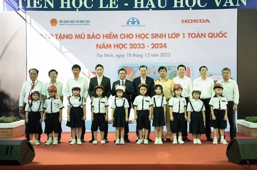 Các đại biểu trao tặng mũ bảo hiểm cho các em học sinh lớp Một trường Tiểu học Trương Định