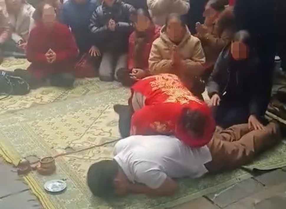 Bà Ch mặc áo đỏ, đầu đóng khăn có biểu hiện nhập "thần hổ" với biểu hiện mê tín dị đoan tại chùa Hương Tích nên đã bị lập biên bản. Ảnh cắt từ clip.