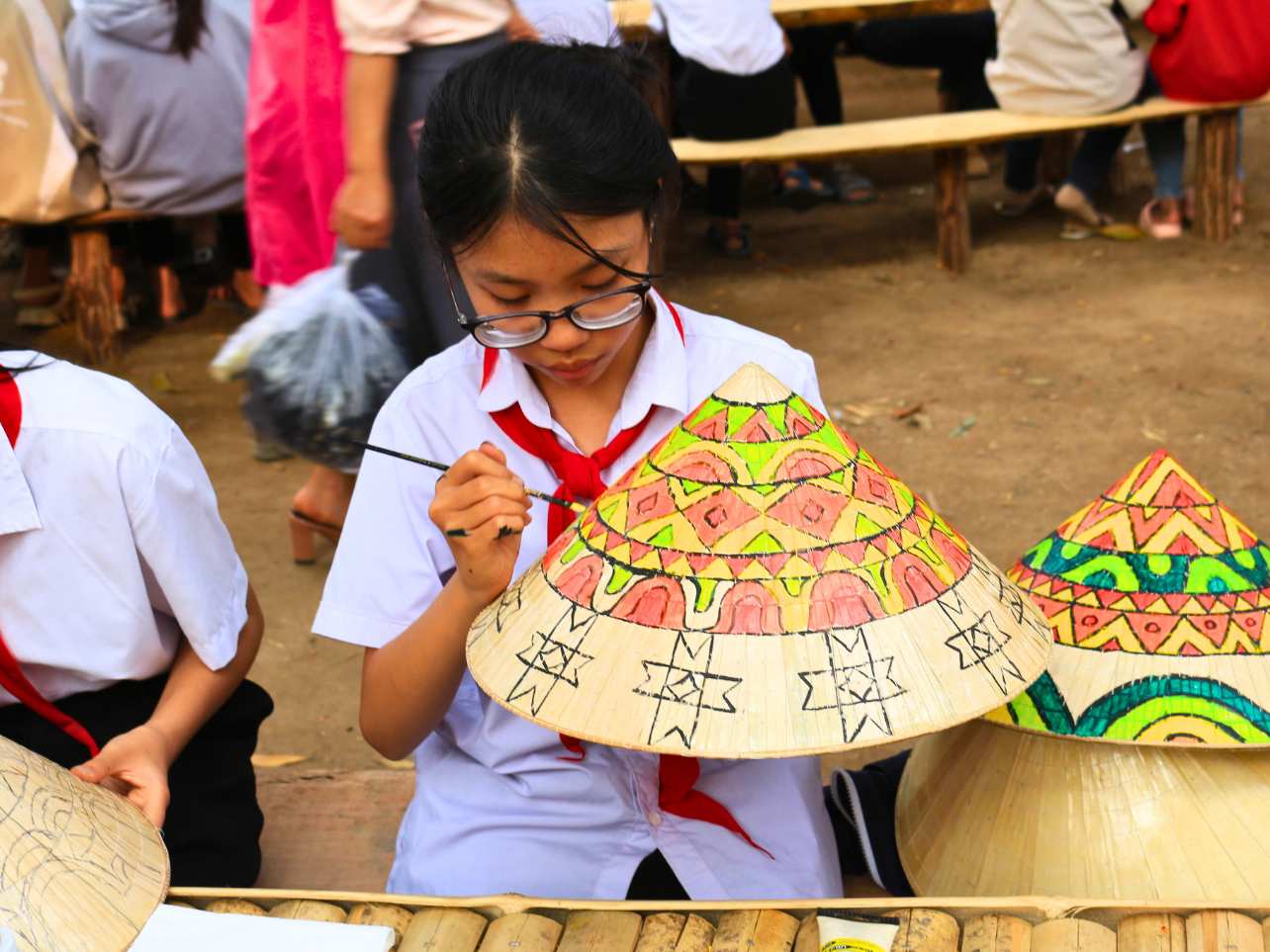 Các em học sinh đến từ trường THCS thị trấn Đăk Hà với mô hình thiết kế nón độc đáo. Em Ngô Thị Hoa (lớp 9A) chia sẻ: “Thông qua các hình ảnh được vẽ trên nón, chúng em muốn truyền tải văn hóa, con người Kon Tum đến với các du khách.” Ảnh: Lê Nguyên 