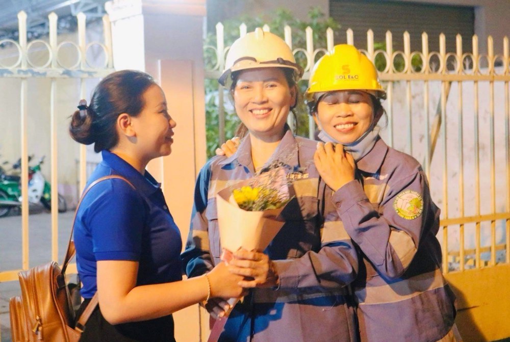 Những nụ cười của nữ công nhân môi trường khi bất ngờ nhận được hoa mừng 8.3 lúc giữa đêm. Ảnh: Đào Hùng