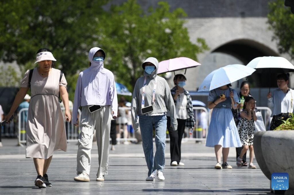 Người đi bộ che chắn khỏi nắng nóng trên đường phố Bắc Kinh, Trung Quốc mùa hè 2023. Ảnh: Xinhua