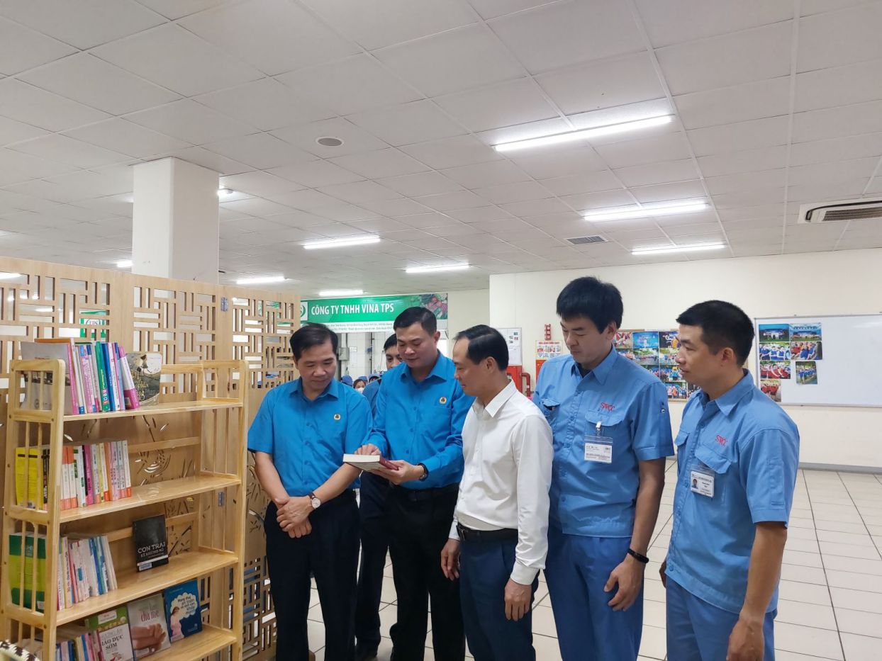 Cán bộ Công đoàn Thành phố và lãnh đạo doanh nghiệp trao đổi về các đầu sách có trên giá sách tại Điểm sinh hoạt văn hóa Công nhân Công ty TNHH SWCC Showa Việt Nam. Ảnh: CĐKCN