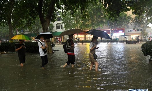 Người dân lội qua con đường ngập nước ở Trịnh Châu, thủ phủ tỉnh Hà Nam, miền trung Trung Quốc trong một đợt mưa lũ. Ảnh: Xinhua