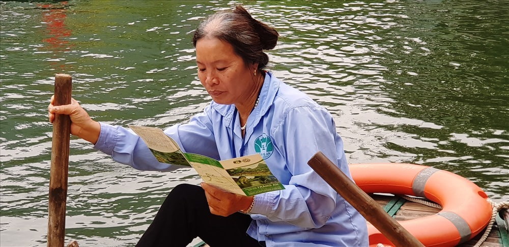 Tranh thủ thời gian trong lúc chờ khách, bà Nguyễn Thị Ngát, cập nhật thêm các thông tin về Di sản Tràng An để giới thiệu đến du khách. Ảnh: Nguyễn Trường