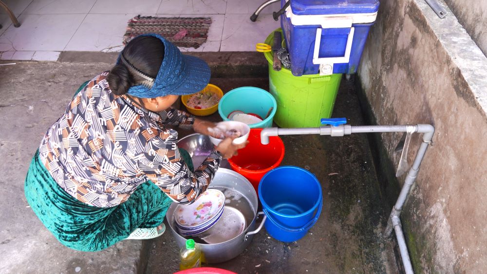 Chị Kim Tươi và một số thành viên trong gia đình liên tục phải chở từng can nước từ trong nhà ra cửa hàng để sử dụng. Ảnh: Tạ Quang