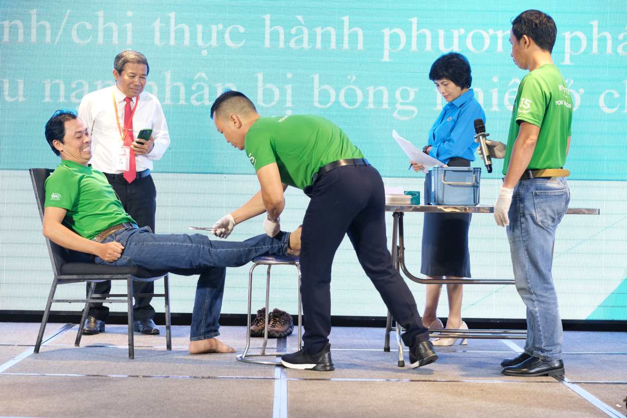 Phần thi thực hành phương pháp sơ cứu nạn nhân bị bỏng nhiệt ở chân của đội CĐCS Công ty TNHH Hải Yến. Ảnh: Quỳnh Anh