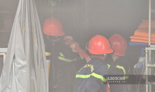 Lực lượng Cảnh sát PCCC mở một đường nước từ tầng 1 cửa hàng vật liệu xây dựng lên tầng 2 để khống chế đám cháy. Ảnh: Đoàn Hưng