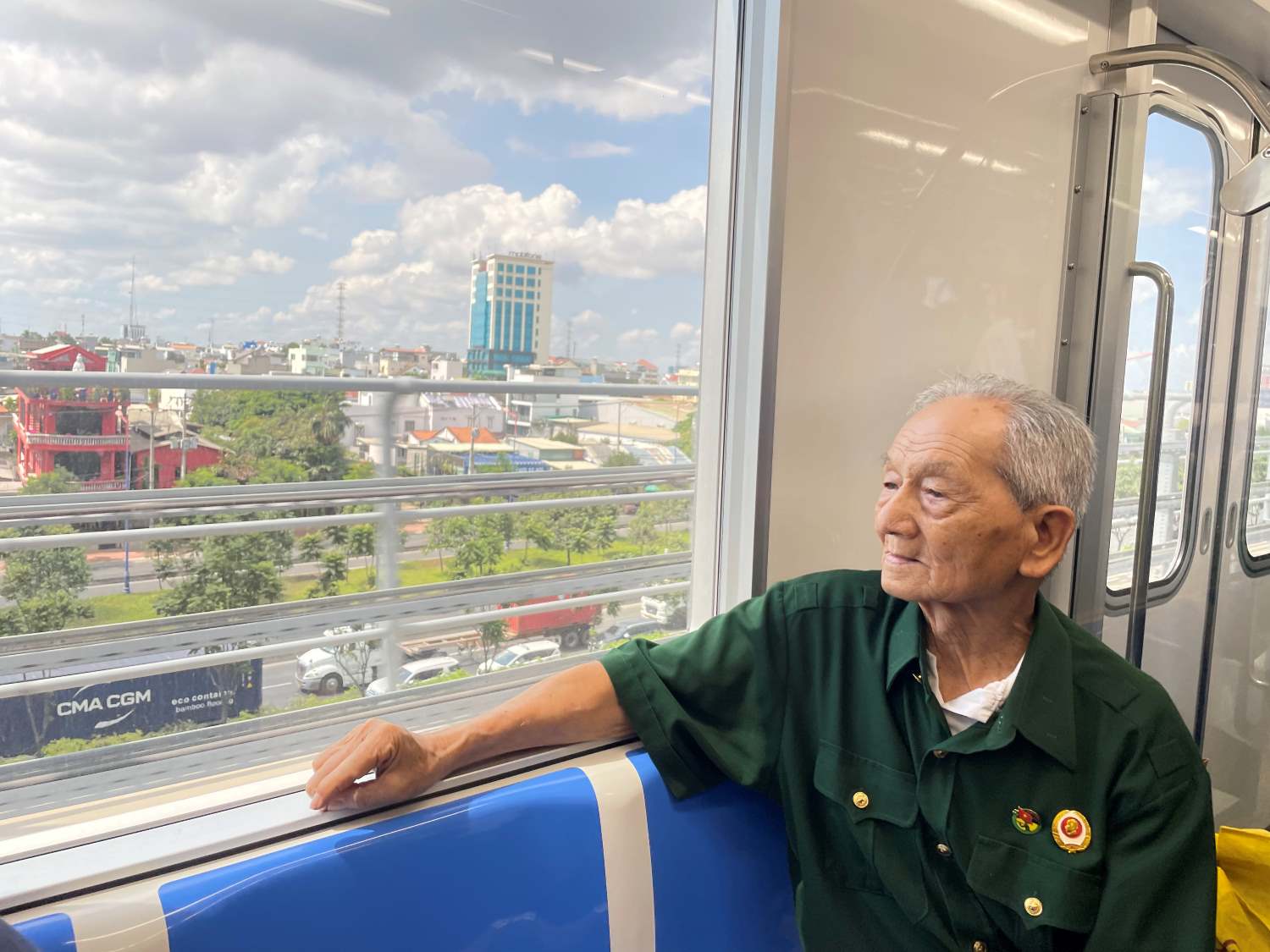 Cựu chiến binh Trịnh Hữu Cán (93 tuổi) ngắm TPHCM từ trên cao qua khung cửa Metro số 1.  Ảnh: Minh Quân