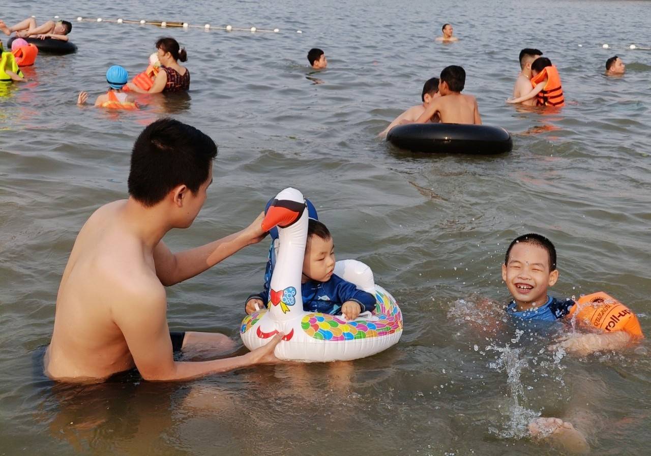 Trẻ nhỏ vui đùa dưới làn nước xanh mát tại bãi biển Tuần Châu.