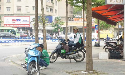 Nhiều tài xế xe ôm công nghệ tìm các bóng cây để tránh nắng tại Hà Nội. Ảnh: Nhật Minh