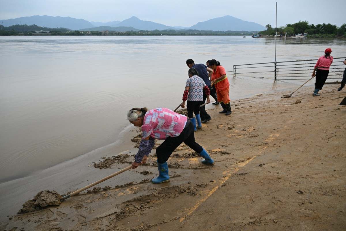 Người dân dọn dẹp ở bờ sông Bắc Giang, thành phố Thanh Viên, phía bắc tỉnh Quảng Đông ngày 24.4.2024. Hơn 100.000 người đã được sơ tán vì mưa lớn và lũ lụt. Ảnh: AFP