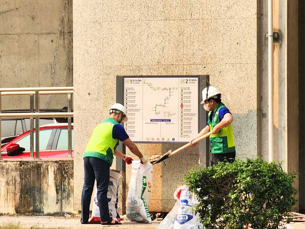 Đoàn Thanh niên Ban Quản lý đường sắt đô thị Hà Nội đang dọn rác thải tại chân các ga tuyến đường sắt Nhổn - ga Hà Nội. Ảnh: BRM