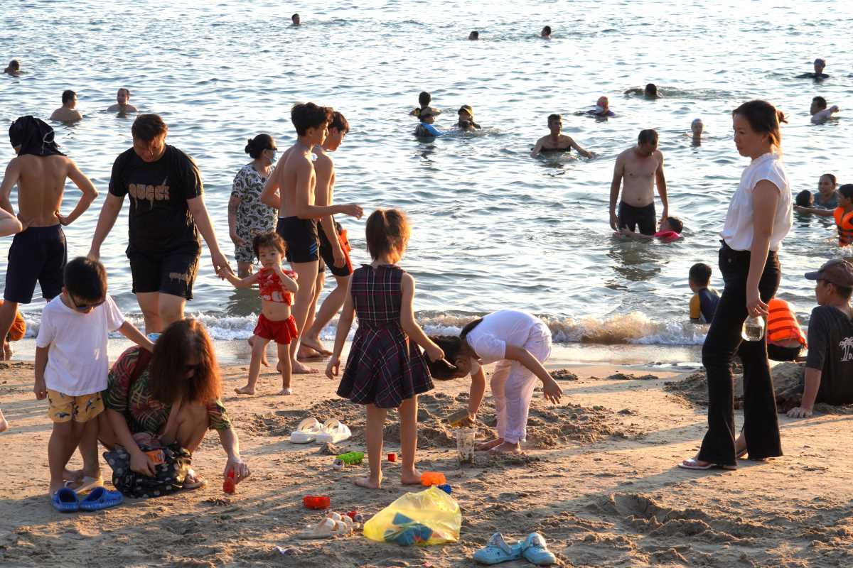 Trông con và cháu gái cùng chơi cát, chị Chi (ngụ Phường 3, áo trắng) cho biết, thời tiết nóng nên tranh thủ rảnh rỗi chở các cháu ra biển giải nhiệt, và giải quyết 