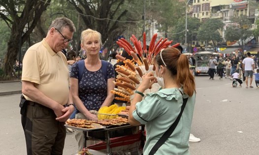 Du khách nước ngoài khám phá ẩm thực đường phố Hà Nội. Ảnh: Ý Yên
