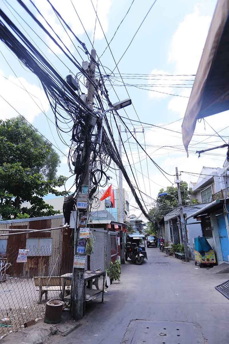 Trong các con hẻm trên đường Quốc lộ 50 (huyện Bình Chánh), dây điện, cáp viễn thông nằm sát với nhà người dân, không đảm bảo an toàn.