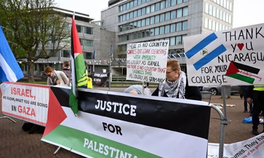 Người biểu tình ủng hộ Palestine cầm biểu ngữ bên ngoài ICJ ở The Hague, Hà Lan, ngày 8.4.2024. Ảnh chụp màn hình