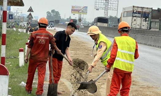 Lực lượng CSGT Nghệ An và công nhân lao động phối hợp xử lý vệt dầu loang trên Quốc lộ 1A. Ảnh: Văn Hậu
