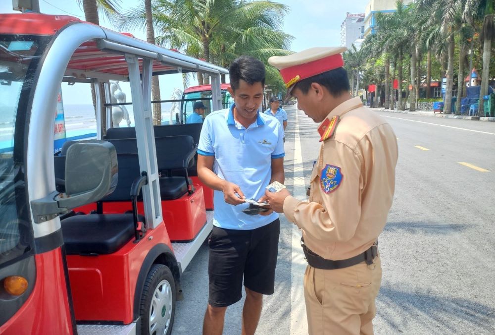 Lực lượng chức năng tiến hành kiểm tra các giấy tờ liên quan đối với tài xế xe điện 4 bánh ở khu du lịch biển Hải Tiến. Ảnh: Minh Hoàng