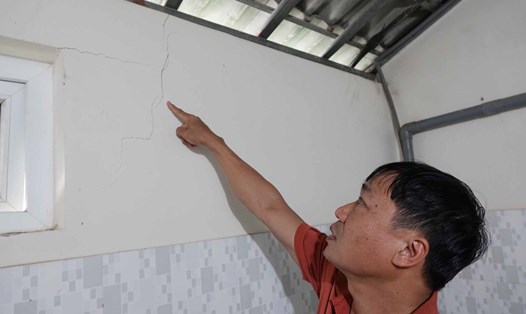 Ông Trịnh Bá Lữ chỉ vết nứt trên tường nhà mình do thi công Quốc lộ 8A. Ảnh: Trần Tuấn