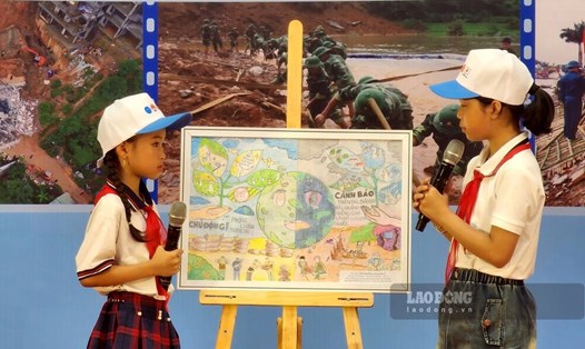 2 học sinh đạt giải nhất cuộc thi sáng tác tranh “Góc nhìn trước thiên tai” thuyết minh về tác phẩm của mình tại Lễ mít tinh. Ảnh: Tô Công