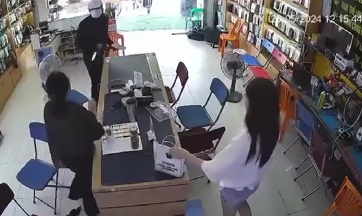 Hình ảnh người đàn ông cầm vật giống dao, súng xông vào cửa hàng để cướp điện thoại. Ảnh cắt từ video clip. 
