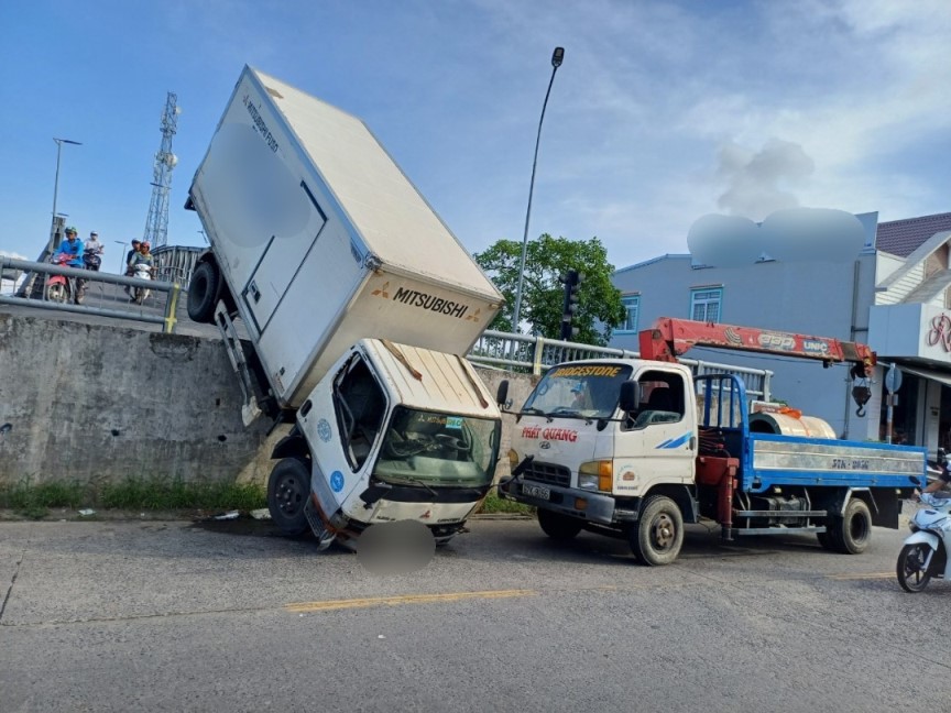 Chiếc xe tải gặp tai nạn mắc lơ lửng thân sau trên cầu. Ảnh: Xuân Nhi
