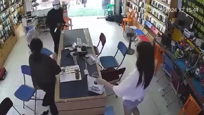 Hình ảnh thủ phạm cầm vật giống dao, súng xông vào cửa hàng để cướp điện thoại. Ảnh cắt từ video clip.