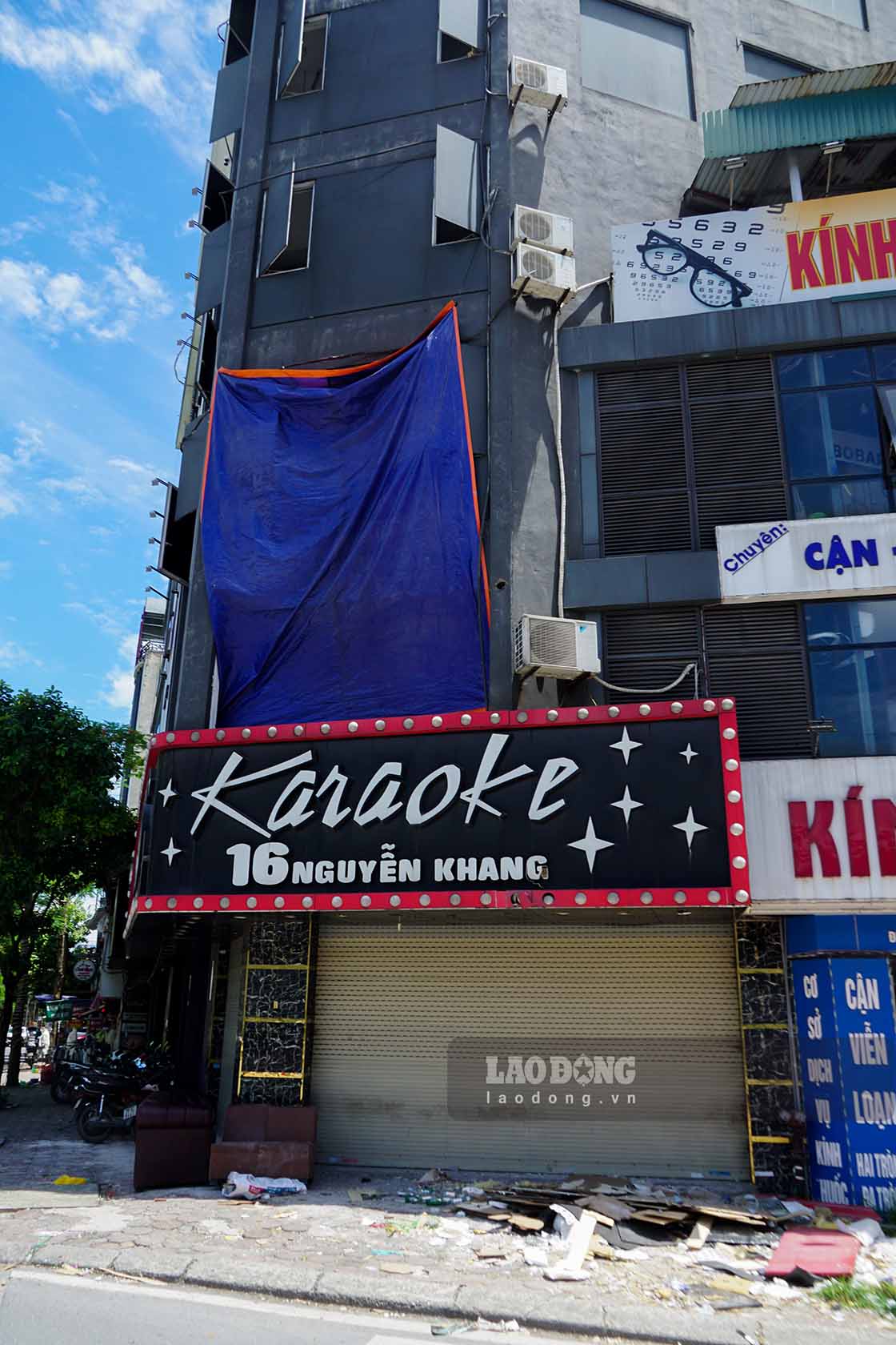 Trong ảnh là quán karaoke tại số 16 đường Nguyễn Khang đã dừng hoạt động từ lâu. Bên ngoài mặt tiền quán ngổn ngang rác thải, bàn ghế cũ được để ngay cửa ra vào.