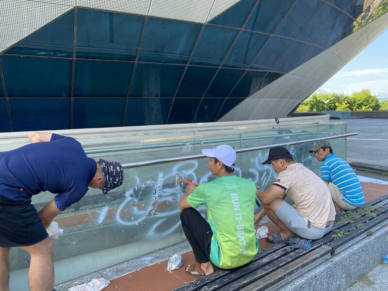 Cán bộ, công nhân ra quân dọn dẹp các hình vẽ bôi bẩn ở xung quanh cung thể thao Tiên Sơn. Ảnh: Trần Thi