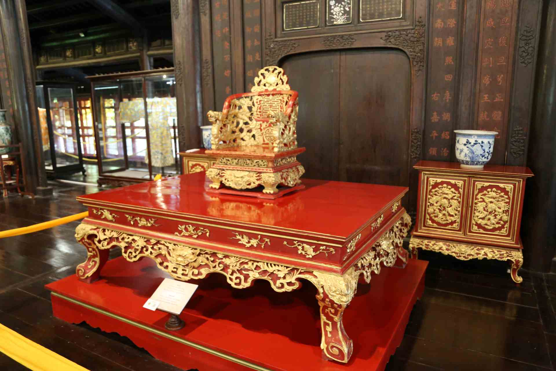 “Ngai vua thời Nguyễn” - Ngai được làm bằng chất liệu gỗ sơn son thếp vàng. Ở phần trên là hình ảnh mặt trời trên nền dải mây cách điệu thể hiện quyền lực tối cao của nhà vua. Ở lưng ngai được khắc hai chữ thọ. Tay ngai 2 bên là 2 hình rồng hướng ra phía trước trong tư thế đạp mây uy nghi thể hiện sức mạnh của vua chúa. Phần dưới là đế được trang trí hoa văn chữ vạn cùng những hàng cánh sen và đồ án lưỡng long chầu chữ thọ. Chân ngai được chạm khắc hổ phù, kiểu long hàm thọ, hoa văn chim phượng.