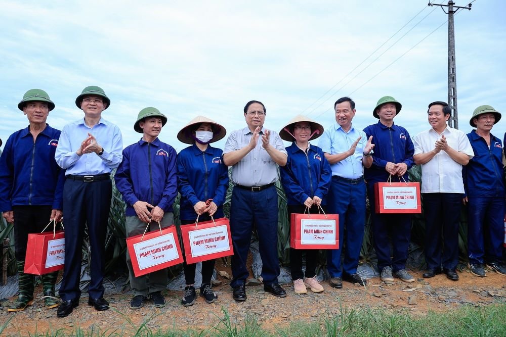 Thủ tướng Phạm Minh Chính tặng quà cho công nhân nông trường trồng dứa Đồng Giao. Ảnh: Nguyễn Hải