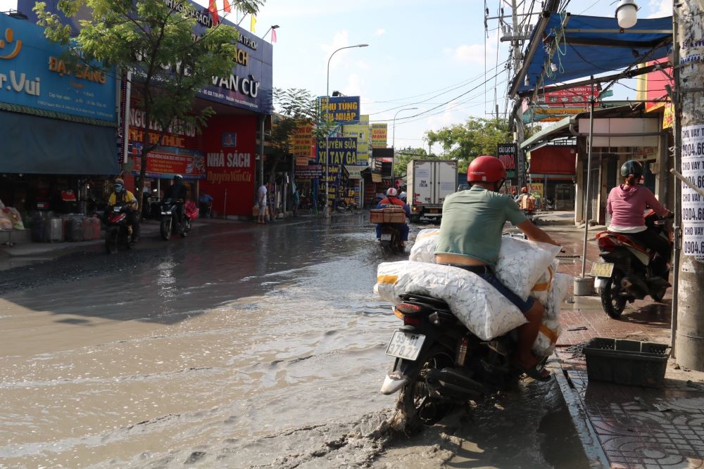 Người dân tìm cách đi trên vỉa hè để tránh hố nước trên đường.