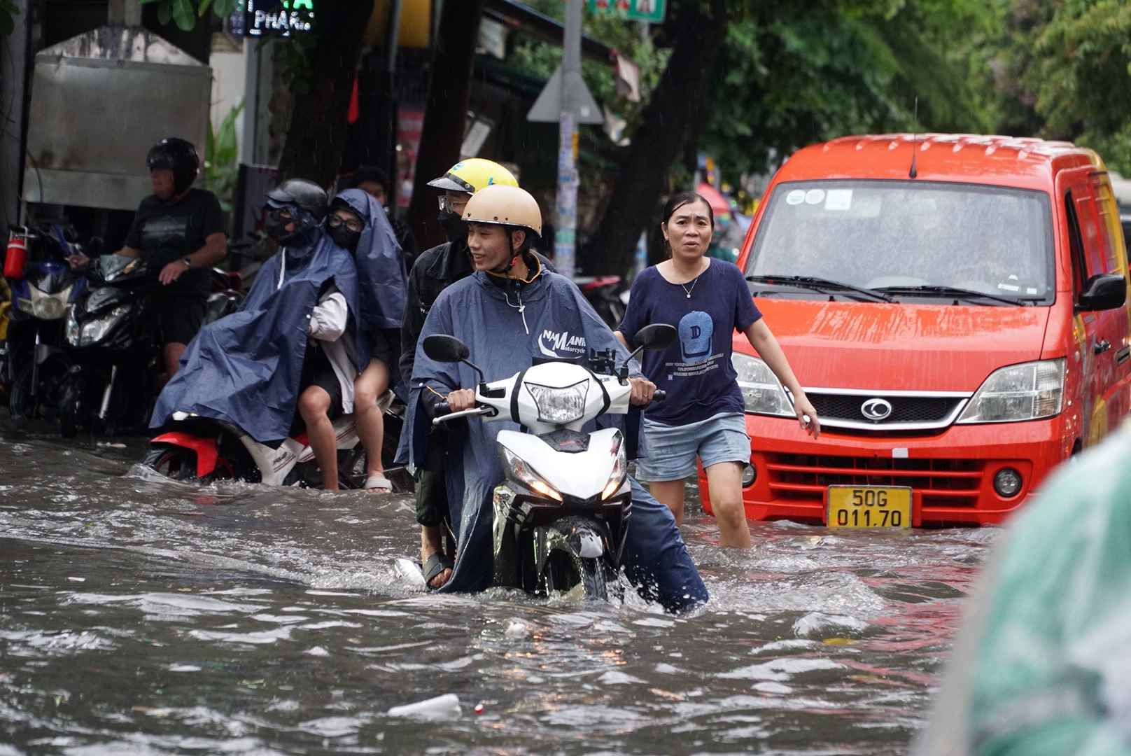 Nhiều người dân ở đây phải vật lộn với nước ngập, lội nước thậm chí nhiều người phải cho xe leo lề chờ nước rút mới dám đi tiếp.